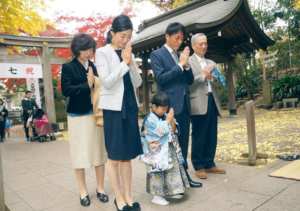 手を合わせてお参りする家族