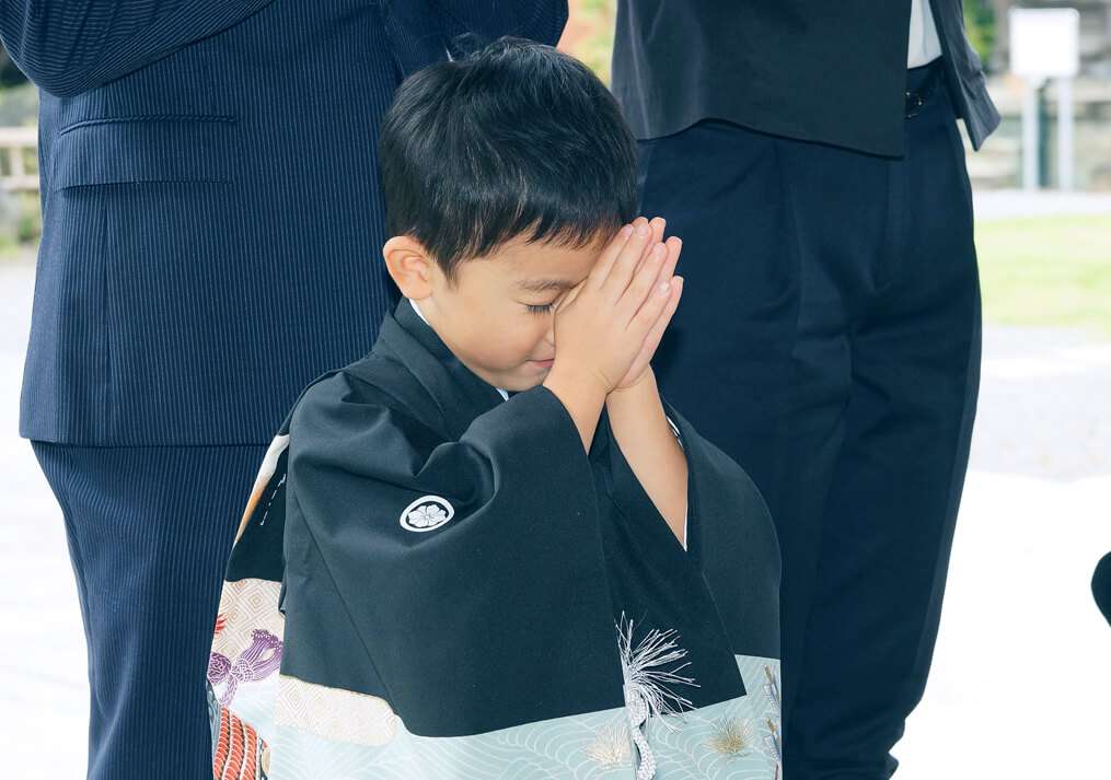 七五三のお参りで手をあわせる男の子