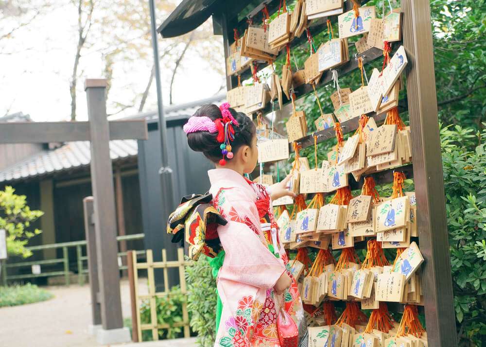 松陰神社の絵馬の前に立つ7歳女の子