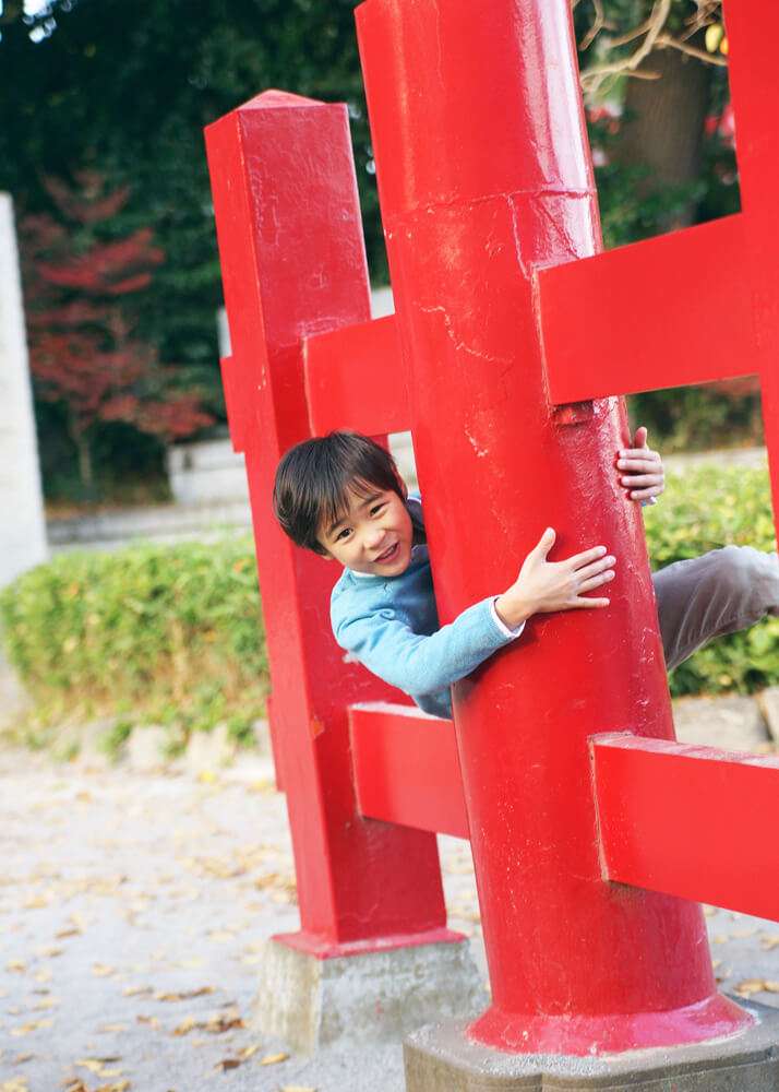 赤い鳥居にしがみつく男の子