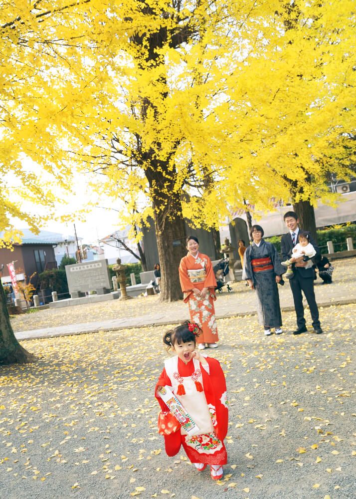 登戸稲荷神社の銀杏並木の下を走る七五三の女の子