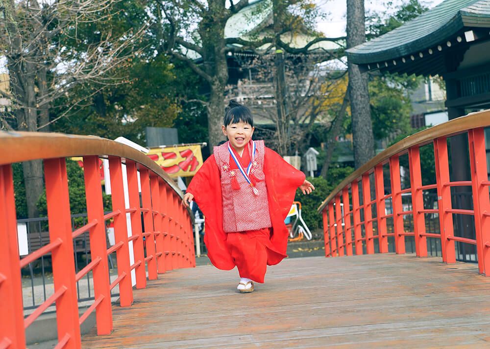 川崎大師の赤い橋を渡る七五三の女の子