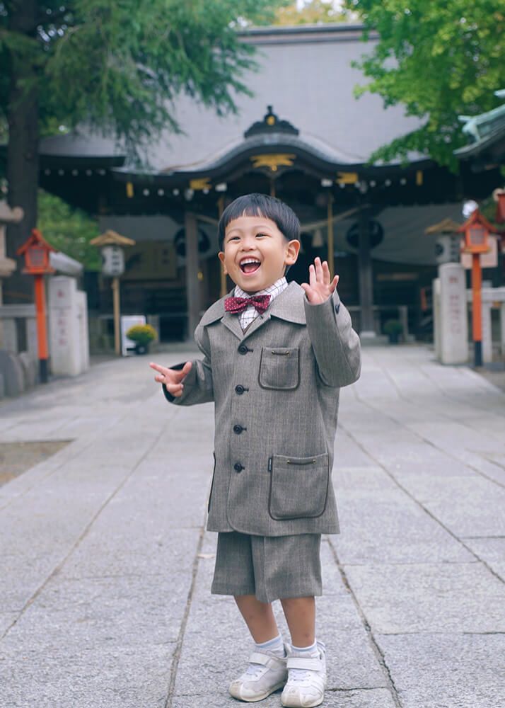 草加神社の参道で飛び跳ねる洋装の七五三の男の子