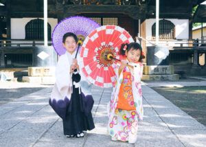 柴又帝釈天の境内で和傘で遊ぶ七五三の兄妹