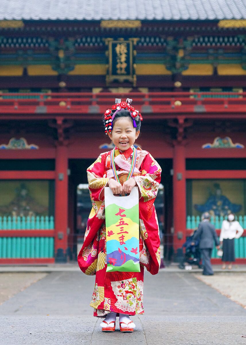 根津神社の楼門の前で千歳飴を持ってポーズをとる女の子