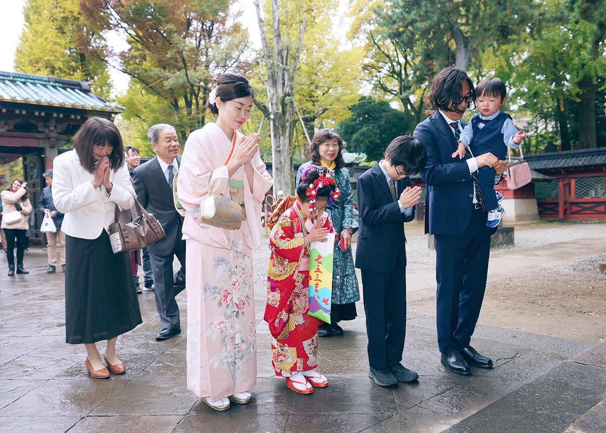 根津神社の拝殿前でお参りをする家族