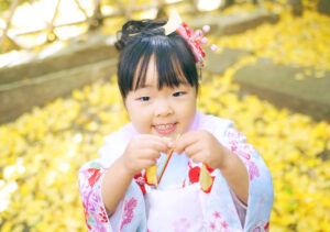 王子神社でイチョウの葉っぱを集める七五三の女の子