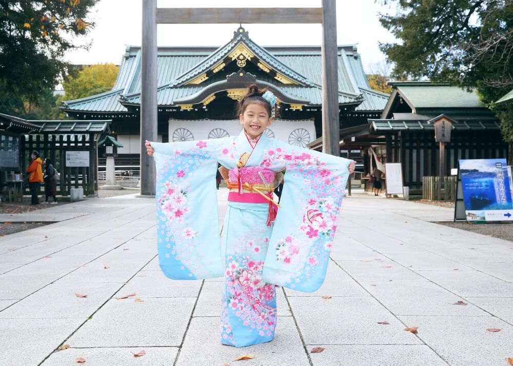 靖国神社の本殿前でポーズをとる七五三の女の子