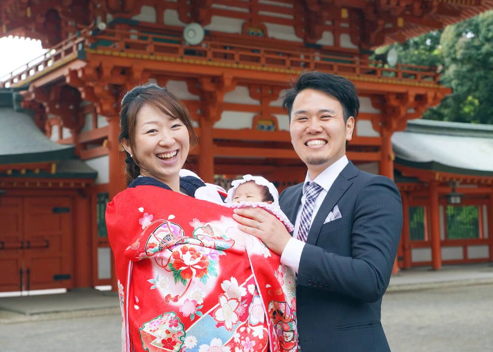 大宮氷川神社の楼門前で赤い祝い着をかけたママ