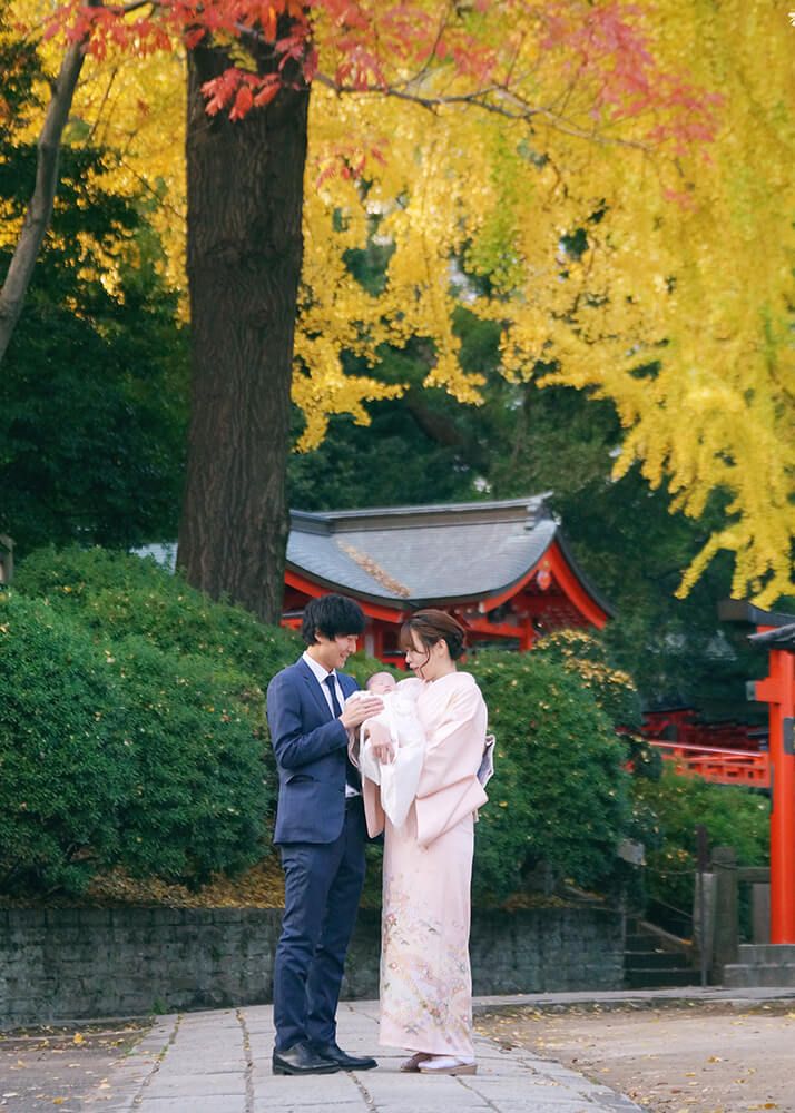 根津神社の紅葉の下でお宮参りの赤ちゃんを抱っこするママ