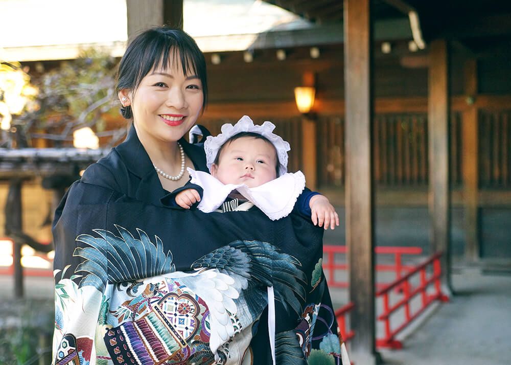 代々木八幡宮のお宮参りで黒色の祝い着・産着（着物）をかけたママ