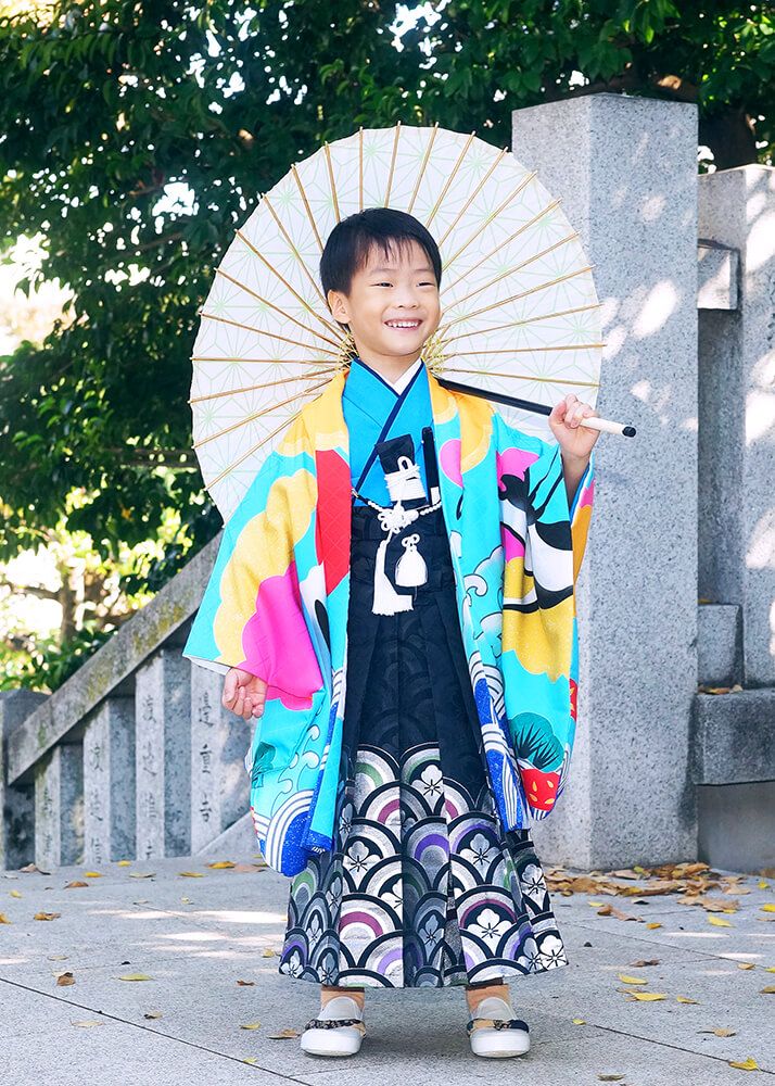 桐ヶ谷氷川神社の境内で和傘を持ってポーズをとる七五三の男の子